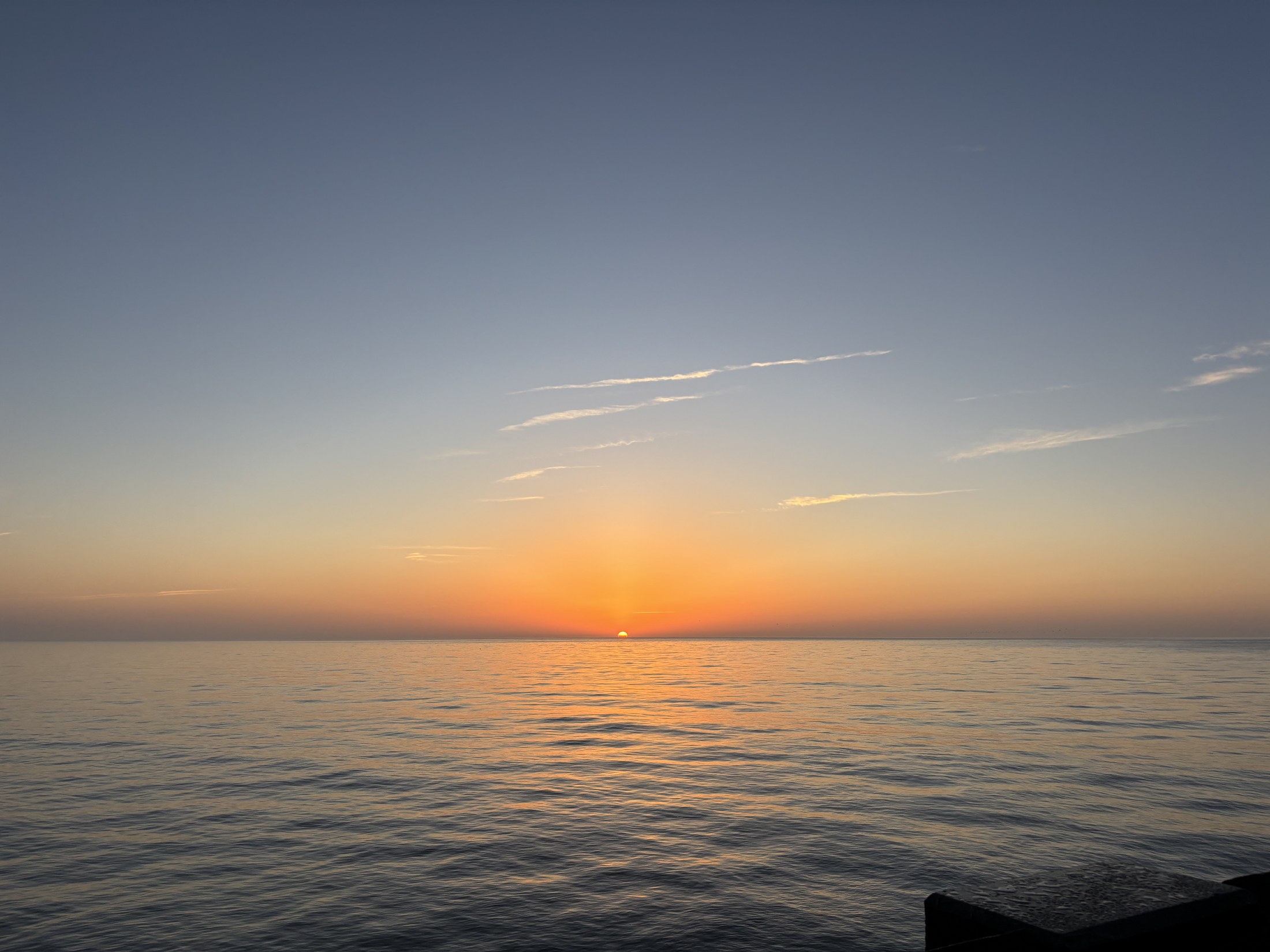 A soft orange horizon over calm Atlantic water at Folly Beach